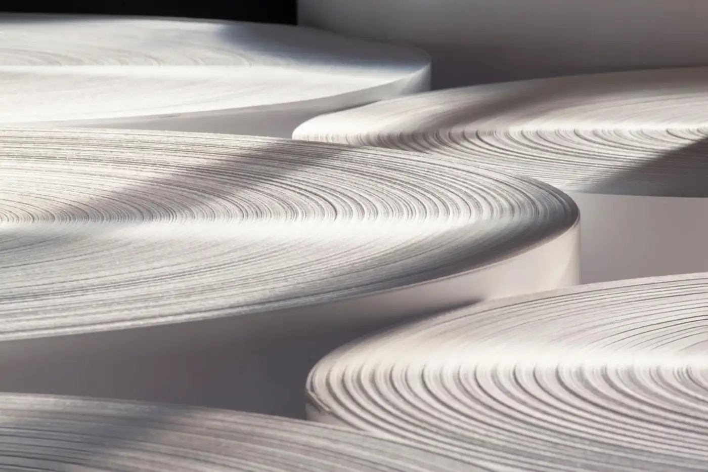 Stacked contour discs in warm white, each layer casting a shadow on the one below